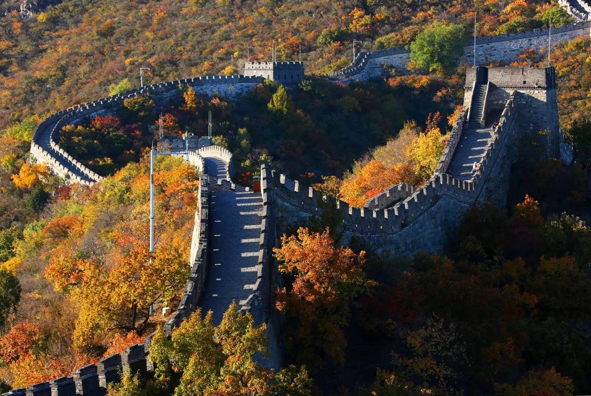 The Great Wall north of Beijing winding through hills covered in red and gold autumn forest