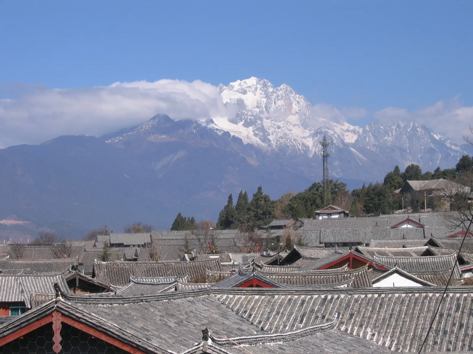 Lijiang's old town rooftops beneath the snow-capped Jade Dragon Snow Mountain in Yunnan